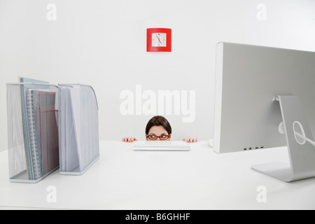 Young businesswoman hiding behind desk Copy space Stock Photo