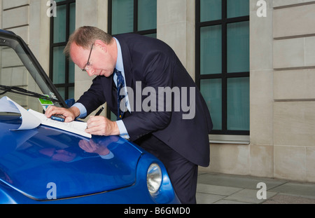 Man signing document on car bonnet Stock Photo