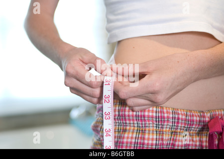 Slender woman measuring her waist with metric tape measure after a diet,  isolated 16406784 PNG