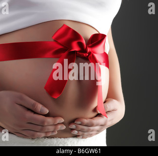 Red bow on a belly of a pregnant woman isolated on black Stock Photo