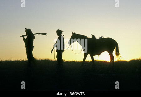 Two mountain men carrying muzzle loader flintlock rifles at sunrise at a Mountain Man rendezvous at Bent s old Fort Stock Photo