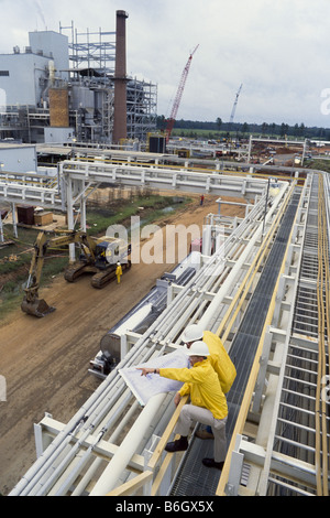 Construction engineers at recycling facility, pipeline leading into factory, Stock Photo