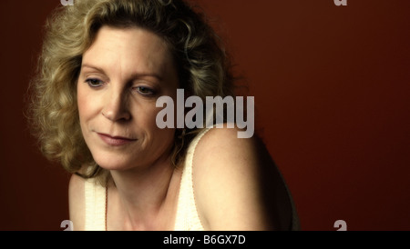 Portrait of a middle aged woman sitting in a chair and looking sad Stock Photo