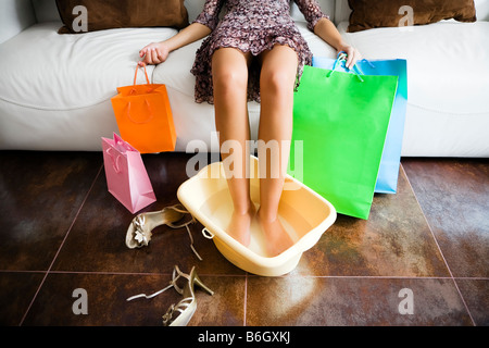 Woman soaking feet in water after long day shopping Stock Photo