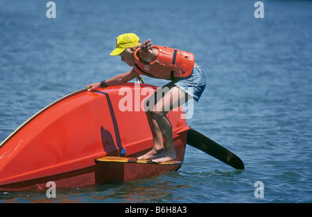 A young boy tries to turn over his sunfish sailboat on a lake on the Pecos River in a Carlsbad NM park Stock Photo