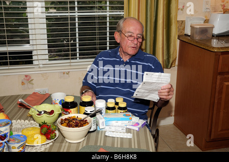 Man at breakfast table with prescribed drug prescription looking at information notes Stock Photo