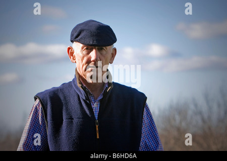 Senior man in flat cap looking thoughtful outside Stock Photo