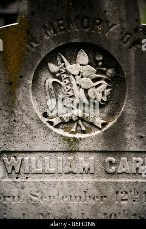 Detail of an old Victorian marble tombstone featuring a symbolic relief carving of a simple bouquet of flowers tied with ribbon. Stock Photo