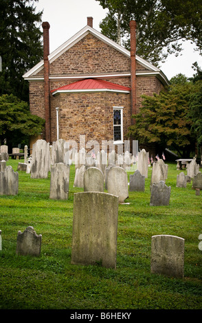 An 18th century early American stone church and cemetery with worn and weathered marble tombstones. Stock Photo