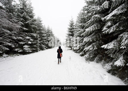 woman walking through a forest in winter Stock Photo