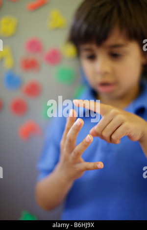 Six year old boy counts on fingers Stock Photo