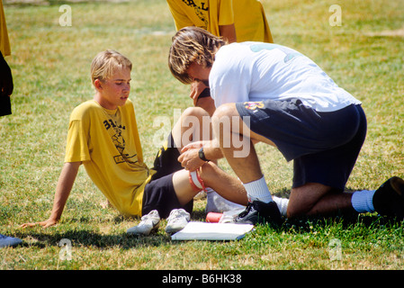 Coach attends injured player in Junior High School football game. Stock Photo