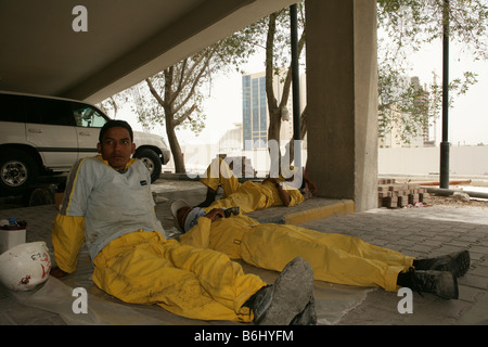 Migrant construction workers taking nap in car park, Doha, Qatar Stock Photo