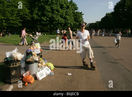 People passing by an overflowing rubbish bin in Hyde park, London. Stock Photo