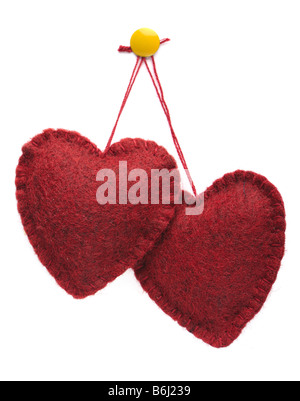 Two felt hearts hanging together on a yellow thumbtack white background Stock Photo