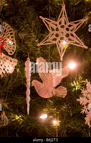 Christmas dove, icicle, star, and snow flake ornaments made of glass, crystal and wool hanging on a tree indoors Stock Photo