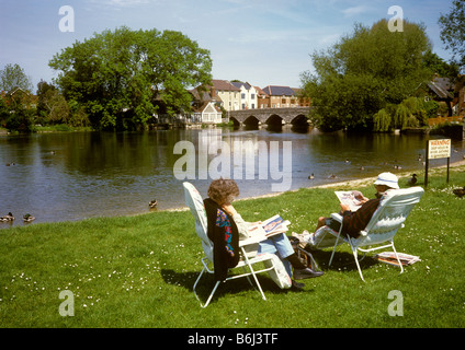 UK England Hampshire Fordingbridge couple relaxing in folding chairs on banks of River Avon Stock Photo