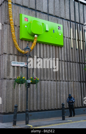 Traffic warden in Ganton Street under a giant electric plug in Soho in London England UK Stock Photo