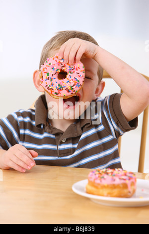 Young boy holding a donut over his eye Stock Photo