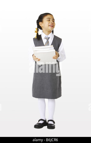 Girl in school uniforms holding three books Stock Photo