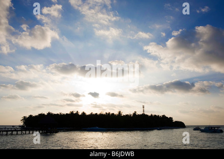 Sun setting behind a tropical island in The Maldives Stock Photo