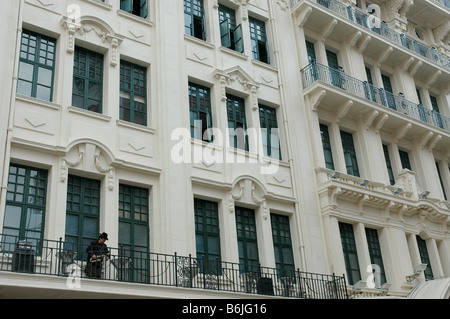 Chinese Man in tuxedo playing saxophone of the balcony of a colonial style building, Shanghai, China Stock Photo