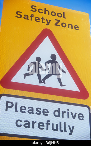 Yellow roadsign with red and white triangle with boy and girl running and School Safety Zone Please drive carefully Stock Photo