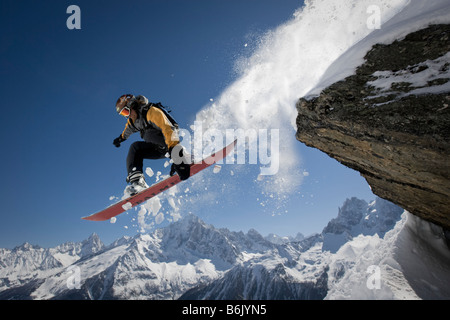 A snowboarder jumps off a rock at Le Brevent, Chamonix, France. Stock Photo