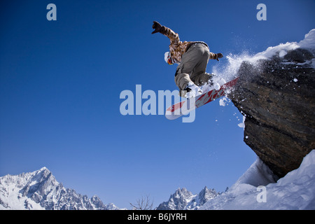 A snowboarder jumps off a rock at Le Brevent, Chamonix, France. Stock Photo