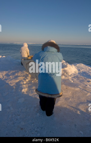 Inupiaq whalers with a seal skin boat or umiak wait and watch for passing bowhead whales at the edge of an open lead Stock Photo