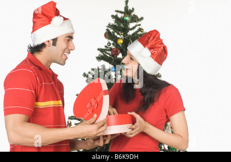 Man giving a heart shaped Christmas present to a woman Stock Photo
