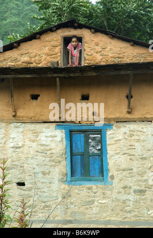 A girl leans out the attic window of a house in Bhorle (near Singati Bazar), Tamakoshi Valley, Dolakha district, Nepal Stock Photo