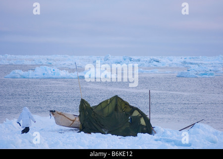 Inupiaq whaling crew pulls their seal skin boat or umiak up onto the pack ice after paddling after whales in an open lead Stock Photo