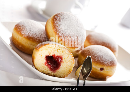 Berliner or Bismarck doughnuts on a plate with cake pliers Stock Photo