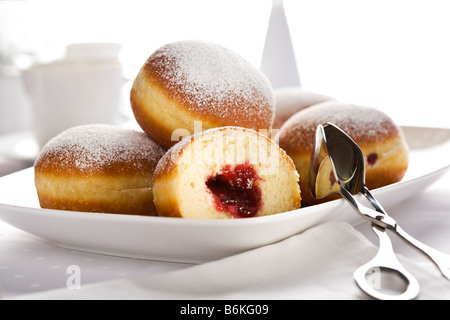 Berliner or Bismarck doughnuts on a plate with cake pliers Stock Photo