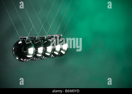 Newtons cradle chrome silver balls hanging on string in studio still life Stock Photo