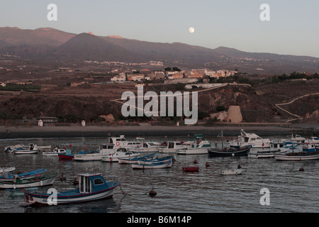 The full moon rising above the harbour of Playa San Juan with the village of Aguadulce behind in Tenerife Canary Islands Spain Stock Photo