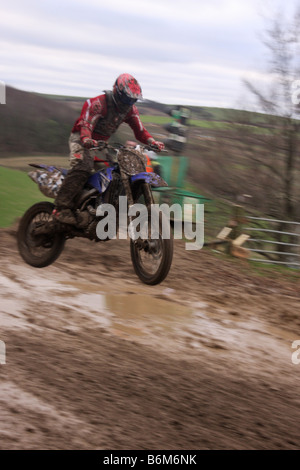 Motocross rider performing jump at dirt track Stock Photo