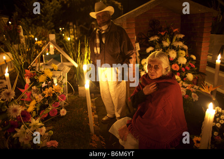A couple sits by the grave of a family member at the cemetery in San Gregorio Atlapulco on the outskirts of Mexico City Stock Photo