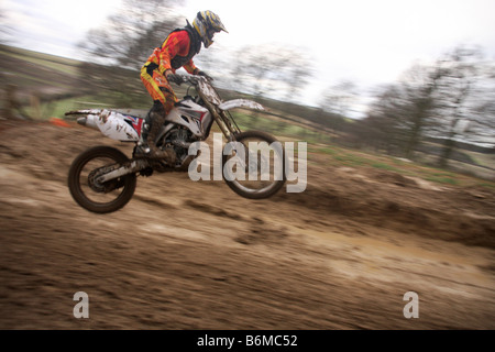 Motocross rider performing jump at dirt track Stock Photo