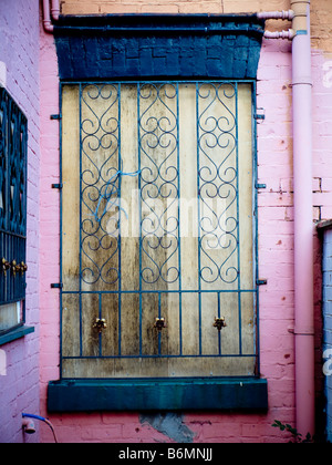 Boarded Up Window with Pink Wall and Security Iron bars Over Wood Stock Photo