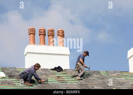Two men with pick axes undertake repairs on the slate roof of Crown House, a former brewery, on Newton green Stock Photo