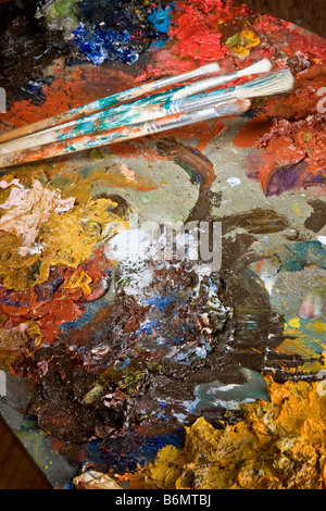 Artist's brushes and colorful pallet full of paint Stock Photo