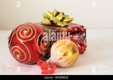 Red  Christmas ball, gold ball and brightly wrapped gift in red foil Stock Photo