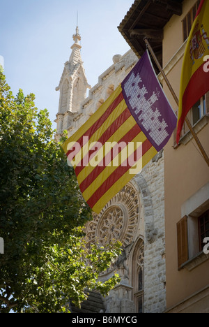 The flag of Mallorca flying outside the town hall in Port De Soller. The church Sant Bartomeu is in the background. Stock Photo