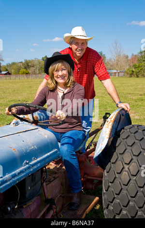Mature married couple riding the tractor on their farm Stock Photo