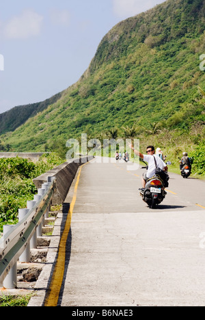 Taiwan, Green Island, Young Man Driving Scooter and looking back gesturing a peace sign Stock Photo