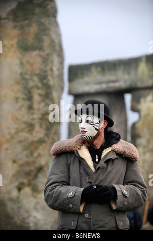 A VISITOR TO STONEHENGE WEARING A WHITEFACE CLOWN MASK DURING THE CELEBRATIONS OF THE WINTER SOLSTICE WILTSHIRE UK Stock Photo