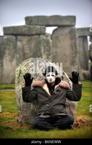 A VISITOR TO STONEHENGE WEARING A WHITEFACE CLOWN MASK DURING THE CELEBRATIONS OF THE WINTER SOLSTICE WILTSHIRE UK Stock Photo