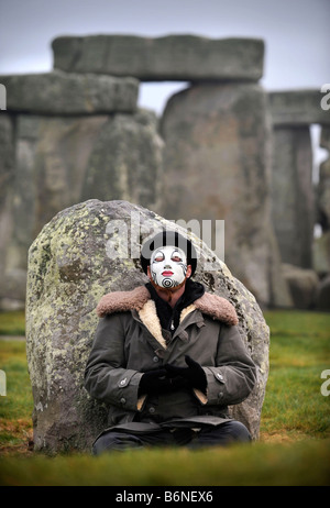 A VISITOR TO STONEHENGE WEARING A WHITEFACE CLOWN MASK DURING THE CELEBRATIONS OF THE WINTER SOLSTICE WILTSHIRE UK Stock Photo